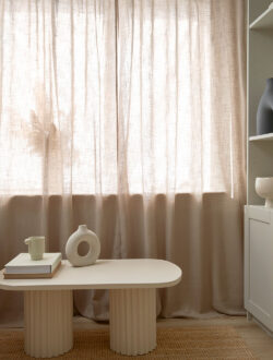 Gartex transparent stofgardin i beige, hvor der foran vinduet står et bord.